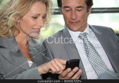 Pair of executives looking at something on a cellphone Pair of executives looking at something on a cellphone stock photo, Pair of executives looking at something on a cellphone by photography33