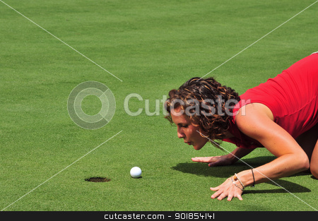 The Last Inch The Last Inch stock photo, A pretty lady golfer attempts to blow a ball into the hole with a breath of air by Jim Fitzroy