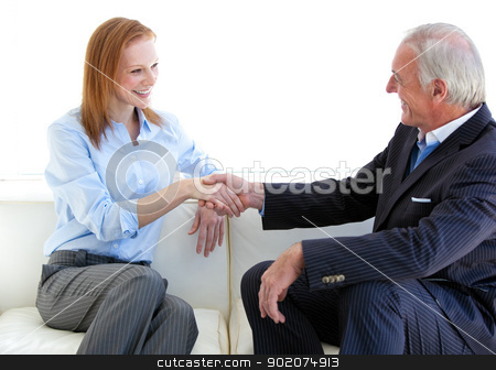Smiling business people shaking hands sitting on a sofa Smiling business people shaking hands sitting on a sofa stock photo, Smiling business people shaking hands sitting on a sofa in a modern building by Wavebreak Media