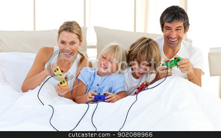 Adorable family playing video game in the bedroom Adorable family playing video game in the bedroom stock photo, Adorable family playing video game lying on bed by Wavebreak Media
