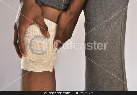 To use this stock image in your creative project, please select the size you need over to the right and click the "Add to Cart" button.
Your downloaded image will come with the Cutcaster watermark removed so don’t worry about the watermark you see on this page. Knee pain stock photo, Closeup of male athlete clutching knee wrapped in sports bandage on grey background by Chad Zuber