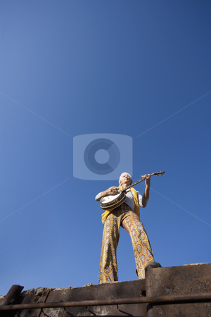 To use this stock image in your creative project, please select the size you need over to the right and click the "Add to Cart" button.
Your downloaded image will come with the Cutcaster watermark removed so don’t worry about the watermark you see on this page. Banjo Player stock photo, Banjo Player with groovy clothes against a wide sky by Scott Griessel