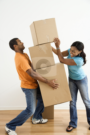 Couple with moving boxes. Couple with moving boxes. stock photo, African American female placing boxes on large stack man is holding. by Iofoto Images