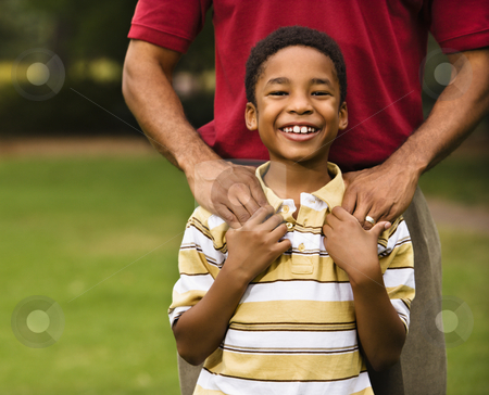 Father and son Father and son stock photo, Father standing behind son with hands on his shoulders as boy smiles. by Iofoto Images