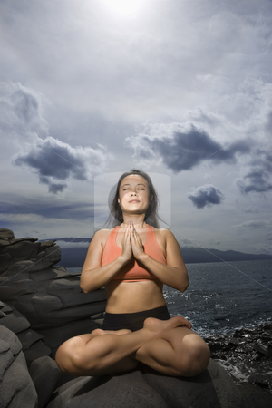 Woman meditating Woman meditating stock photo, Asian woman sitting on rock by ocean in lotus pose with eyes closed in Maui, Hawaii by Iofoto Images