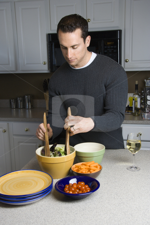 Man making salad. Man making salad. stock photo, Caucasian man making salad on kitchen counter. by Iofoto Images