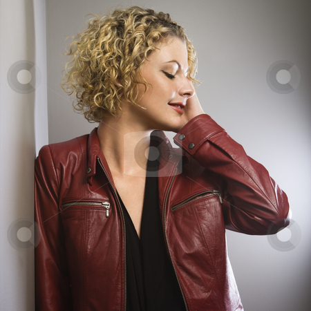 Woman touching face. Woman touching face. stock photo, Caucasian young adult woman in red jacket with hand touching face looking away. by Iofoto Images