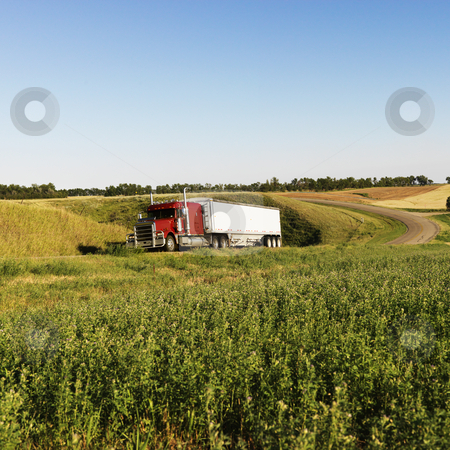 Semi truck on rural road. Semi truck on rural road. stock photo, Semi tractor truck on rural road with green plants on shoulder. by Iofoto Images