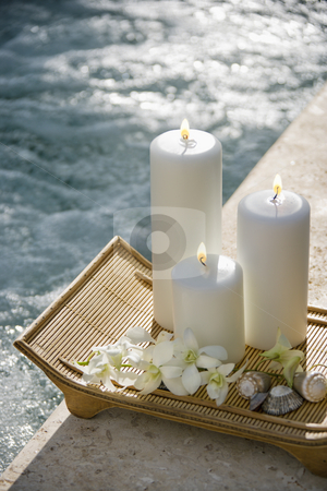 Candles by pool. Candles by pool. stock photo, Lit pillar candles on tray with white orchids beside pool. by Iofoto Images