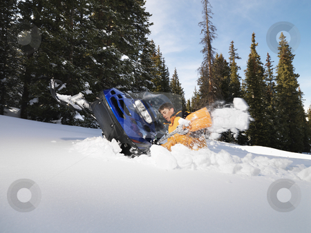 Man with stuck snowmobile. Man with stuck snowmobile. stock photo, Young man digging out snowmobile submerged in the snow. by Iofoto Images