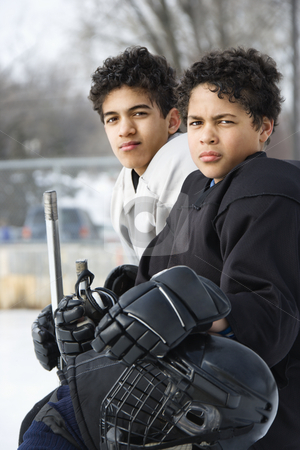 Boys in hockey uniforms. Boys in hockey uniforms. stock photo, Two boys in ice hockey uniforms sitting on ice rink sidelines looking. by Iofoto Images