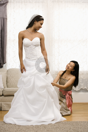 To use this stock image in your creative project, please select the size you need over to the right and click the "Add to Cart" button.
Your downloaded image will come with the Cutcaster watermark removed so don’t worry about the watermark you see on this page. Bridesmaid adjusting bride's dress. stock photo, Asian bridesmaid fixing African-American bride's dress. by Iofoto Images