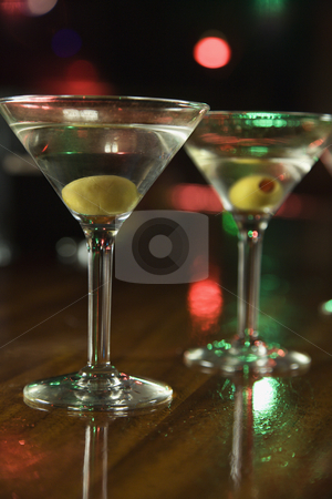 Two martinis on bar. Two martinis on bar. stock photo, Two martinis with olives on bar with red and green lights in background. by Iofoto Images