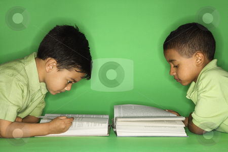 Boys lying and reading. Boys lying and reading. stock photo, Hispanic and African American male child lying reading. by Iofoto Images