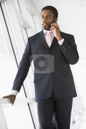 Businessman standing in corridor using cellular phone Businessman standing in corridor using cellular phone stock photo, by Monkey Business Images