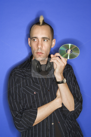 To use this stock image in your creative project, please select the size you need over to the right and click the "Add to Cart" button.
Your downloaded image will come with the Cutcaster watermark removed so don’t worry about the watermark you see on this page. Man holding DVD or Cd. stock photo, Caucasian man with mohawk with headphones holding cd standing against blue background. by Iofoto Images