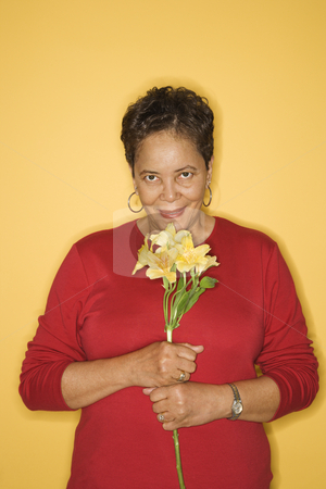 To use this stock image in your creative project, please select the size you need over to the right and click the "Add to Cart" button.
Your downloaded image will come with the Cutcaster watermark removed so don’t worry about the watermark you see on this page. Woman smelling flowers. stock photo, African American mature adult female holding flowers. by Iofoto Images