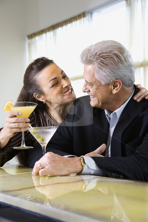 Couple drinking at bar. Couple drinking at bar. stock photo, Caucasian mature adult male and prime adult female sitting at bar with cocktails. by Iofoto Images