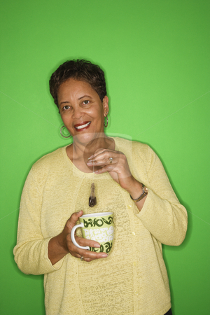 To use this stock image in your creative project, please select the size you need over to the right and click the "Add to Cart" button.
Your downloaded image will come with the Cutcaster watermark removed so don’t worry about the watermark you see on this page. Woman making hot tea. stock photo, African American female mature adult dipping tea bag in mug. by Iofoto Images