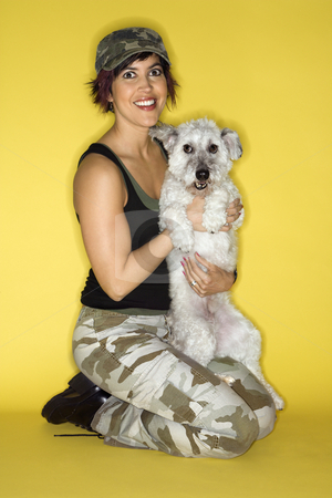 Pretty young woman holding dog. Pretty young woman holding dog. stock photo, Hispanic mid-adult woman kneeling holding small white dog. by Iofoto Images