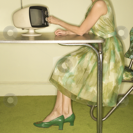 To use this stock image in your creative project, please select the size you need over to the right and click the "Add to Cart" button.
Your downloaded image will come with the Cutcaster watermark removed so don’t worry about the watermark you see on this page. Woman dialing television. stock photo, Side view of Caucasian mid-adult woman wearing green vintage dress sitting at 50's retro dinette set turning old televsion knob. by Iofoto Images