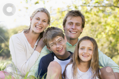 Family sitting outdoors smiling Family sitting outdoors smiling stock photo, by Monkey Business Images
