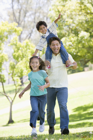 Man with two young children running outdoors smiling Man with two young children running outdoors smiling stock photo, by Monkey Business Images