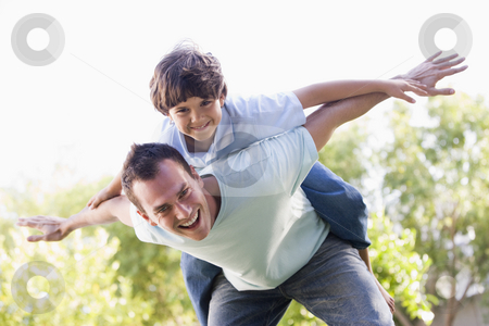 Man and young boy outdoors playing airplane smiling Man and young boy outdoors playing airplane smiling stock photo, by Monkey Business Images