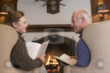 Couple sitting in living room by fireplace with books smiling Couple sitting in living room by fireplace with books smiling stock photo, by Monkey Business Images