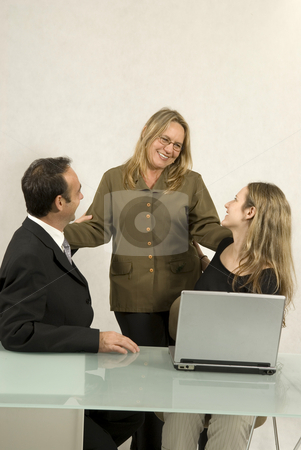 People in Business Meeting - Vertical People in Business Meeting - Vertical stock photo, Three people are in a business meeting. They are smiling and looking at each other. There is a laptop on the table. Vertically framed shot. by Orange Line Media