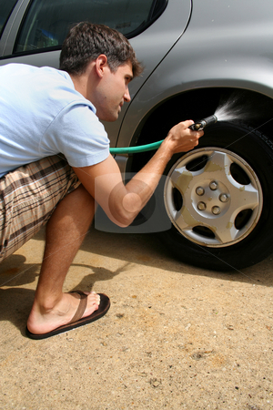 Man Washing Car - Vertical. Man Washing Car - Vertical. stock photo, A man washing his car. He is using a hose to wash the tires. Vertically framed shot. by Orange Line Media