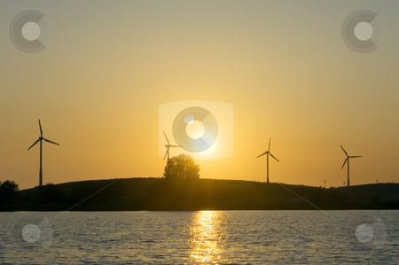 Green Energy Green Energy stock photo, Four windmills lined up on a knoll in front of a blazing sunset by Corepics VOF