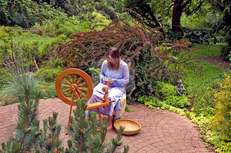 Woman Spinning Woman Spinning stock photo, This Caucasian woman is an artisan hand spinning wool into yarn on her spinning wheel in her beautiful lush garden. by Valerie Garner