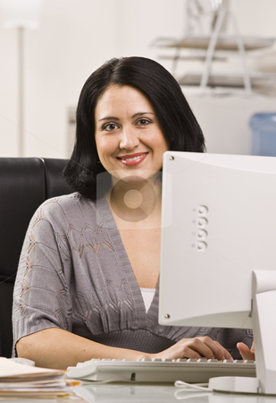 Attractive woman at desk. Attractive woman at desk. stock photo, Attractive woman sitting at desk behind monitor typing on keyboard. Vertical by Jonathan Ross