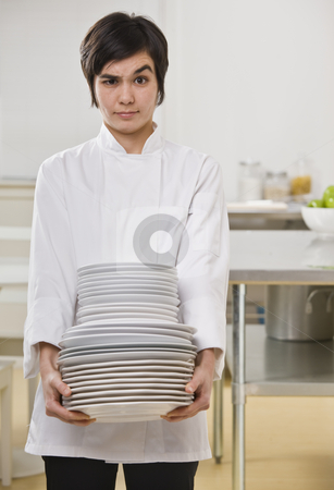 Woman with stack of dishes. Woman with stack of dishes. stock photo, Brunette woman with questioning face, carrying heavy dishes and looking toward camera. Vertical by Jonathan Ross