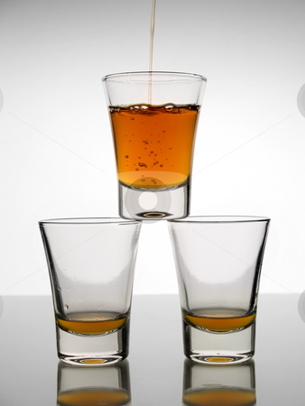 Three shots of whiskey Three shots of whiskey stock photo, A shot being poured with whiskey over other two almost empty shots. by Ignacio Gonzalez Prado