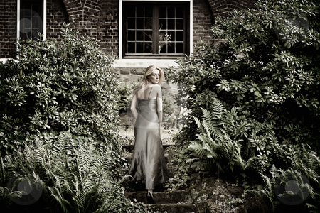 Blond beauty in a castle garden dressed for gala Blond beauty in a castle garden dressed for gala stock photo, Beautifull blond in gala dress walking away from viewer, climbing up some stairs in a castle garden by Frenk and Danielle Kaufmann