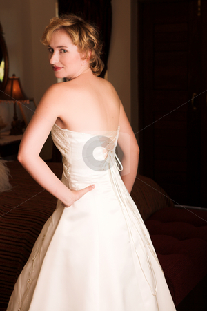Young blonde bride wearing wedding gown Young blonde bride wearing wedding gown stock photo, Young blonde bride with champagne colored wedding gown and red lips. She is looking over her shoulder with an alluring and seductive look in her green eyes. She is in a luxurious bedroom by Sean Nel