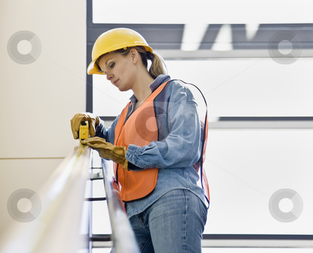 Female Construction Worker Female Construction Worker stock photo, Female construction worker taking measurement with measuring tape. Horizontally framed shot. by Jonathan Ross