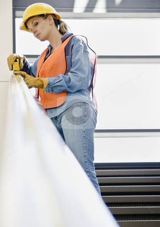 Female Construction Worker Female Construction Worker stock photo, Female construction worker taking measurement with measuring tape. Vertically framed shot. by Jonathan Ross