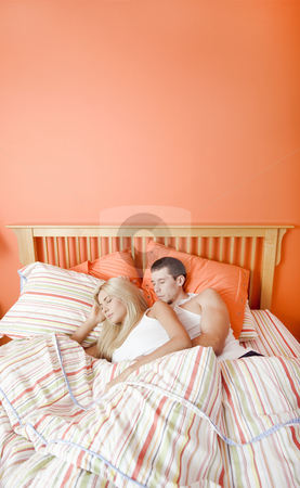 Young Couple Sleeping in Bed Young Couple Sleeping in Bed stock photo, High angle view of young couple sleeping closely together under a striped bedspread. Vertical shot. by Christopher Nuzzaco