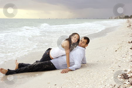 Woman laying on top of man at beach looking at viewer Woman laying on top of man at beach looking at viewer stock photo, A beautiful you lady is laying on top of a man at the beach, their clothes are wet and she is looking at viewer, he has strange expression on his face at sunset. by Stephen Orsillo
