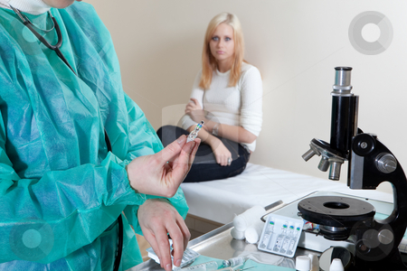 Doctor holding a vaccine Doctor holding a vaccine stock photo, Doctor holding a vaccine in front of patient in background by Ruta Balciunaite