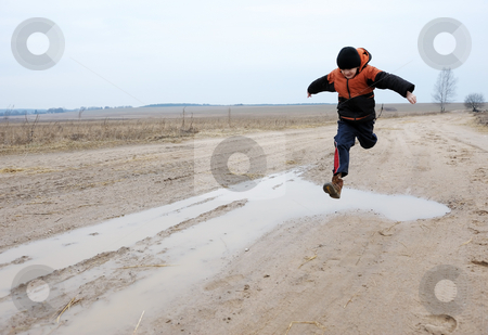 To use this stock image in your creative project, please select the size you need over to the right and click the "Add to Cart" button.
Your downloaded image will come with the Cutcaster watermark removed so don’t worry about the watermark you see on this page. Jumping boy stock photo, A boy jumps over a puddle on a rural road by Vladimir Blinov