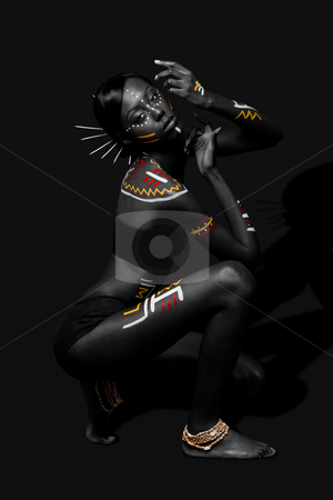 Tribal beauty woman with makeup Tribal beauty woman with makeup stock photo, Beautiful exotic African female fashion with tribal yellow red and white makeup cosmetics and sticks in hair, in cultural dance position. by Paul Hakimata