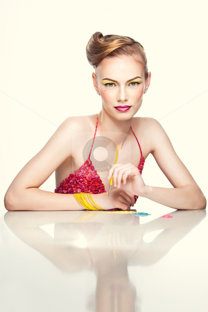 A colorful beauty portrait of a blonde, young woman A colorful beauty portrait of a blonde, young woman stock photo, a studio beauty portrait of a young woman, with colorful makeup and clothes, shot on white background. She holds a makeup brush in one hand as she is trying on different eyeshadow colors. by dan comaniciu