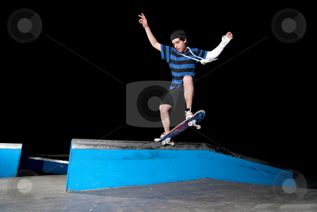 Skateboarder on a slide Skateboarder on a slide stock photo, Skateboarder on a slide at night at the local skatepark. by Homydesign