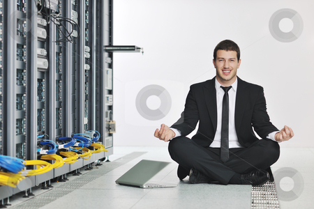 Business man practice yoga at network server room Business man practice yoga at network server room stock photo, young handsome business man in black suit and tie practice yoga and relax at network server room while representing stres control concept by Benis Arapovic