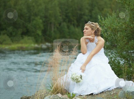 Sad bride sits on river bank Sad bride sits on river bank stock photo, The sad bride sits on river bank and looks afar by Alexey Romanov