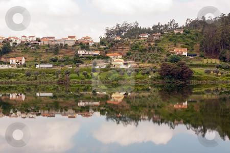 To use this stock image in your creative project, please select the size you need over to the right and click the "Add to Cart" button.
Your downloaded image will come with the Cutcaster watermark removed so don’t worry about the watermark you see on this page. Landscape of a small village with its reflection in the river stock photo, Landscape of a small village with its reflection in the river by Paulo M.F. Pires